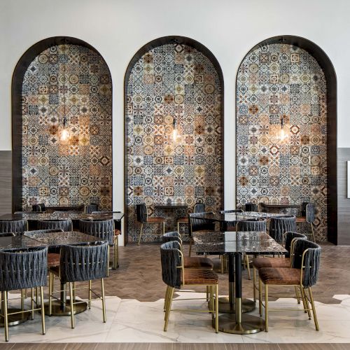 A stylish cafe or restaurant interior with patterned tile arches, cozy seating, and warm lighting, perfect for dining or drinks.