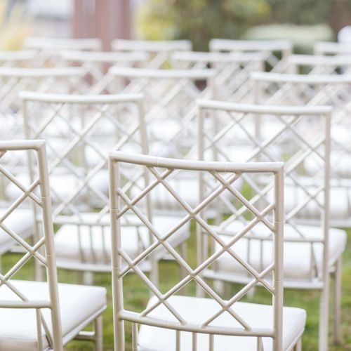 A room with white wire chairs arranged in rows, suggesting a quiet event or ceremony setup.